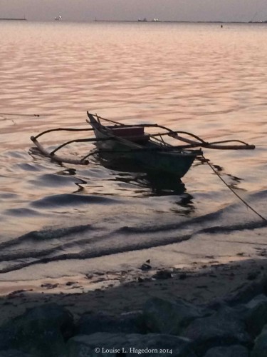 Bangka, a small paddle powered outrigger canoe, anchored near the sea wall at Baywalk, Manila Bay
