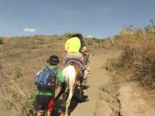 Reggie leaning forward while her horse climbs uphill.